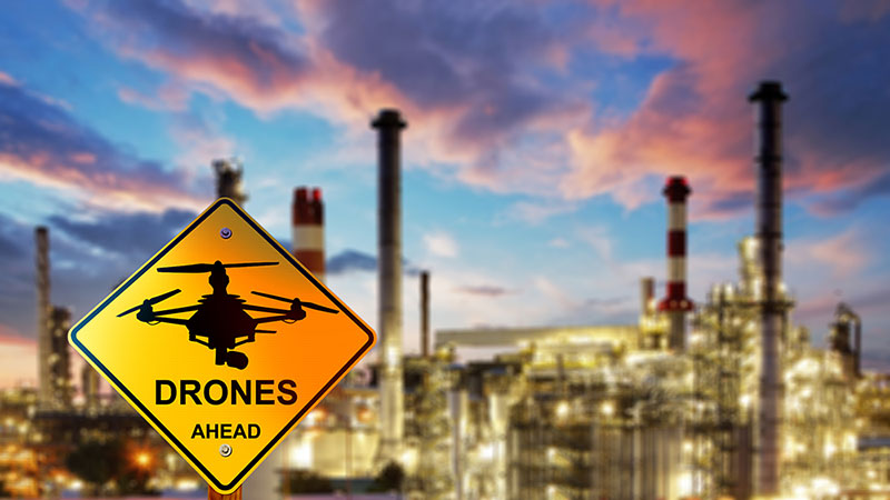 Refinery with a "drones ahead" sign in front of it