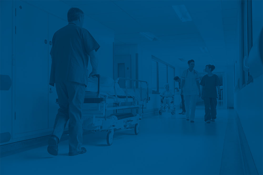 Nurse pushing patient bed through hospital hallway