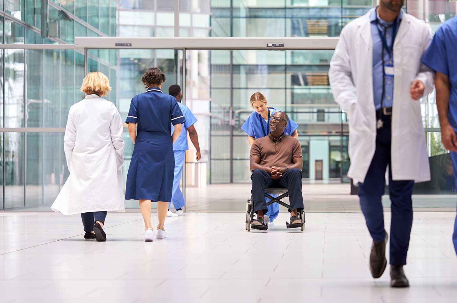 Nurse pushing man in wheelchair in hospital