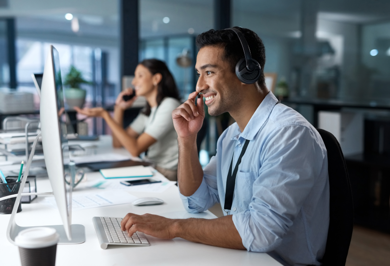 Shows people at their desks talking over a headset and looking at computer screens