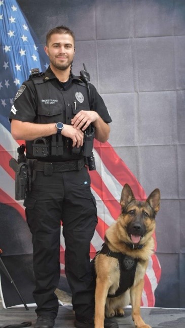 Photo of a man in a security guard uniform with a German Shepherd dog at his site