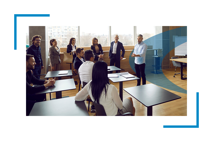 Students in classroom congregate around instructor. 