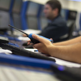 professional sitting at computer with radio in hand