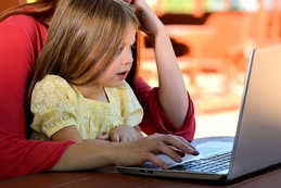 child looking at computer with parent
