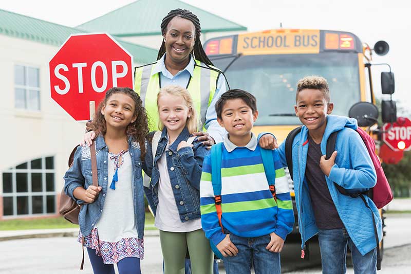 Kids with crossing guard in front of school bus