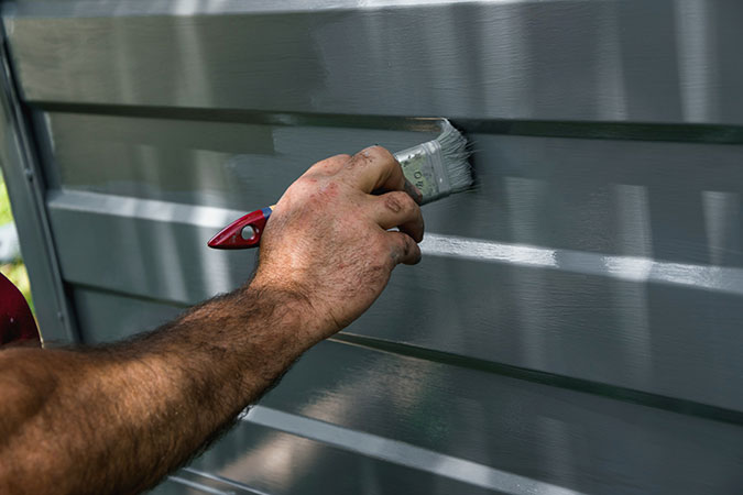 man painting metal to restore it