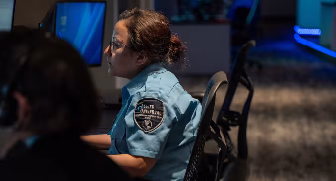 An Allied Universal employee sitting at a computer screen monitoring movement